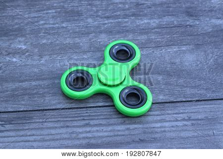 Green fidget spinner stress relieving toy on wooden background.