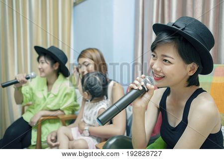 beautiful asian younger woman singing karaoke song at home family relaxing and happy time
