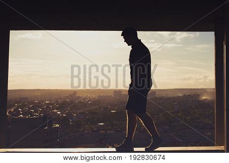A lonely roofer on the roof of the high-rise at sunset. Courage and adrenaline. Loneliness and calmness