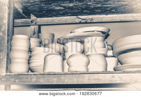 Bright pottery. Many white, not painted clay pottery standing on wooden shelves