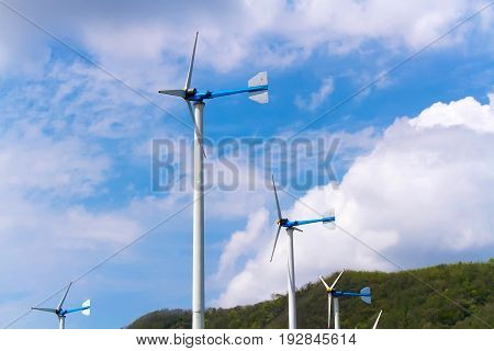eco power : wind turbines generating electricity clean energy with mountain and cloud on blue sky background