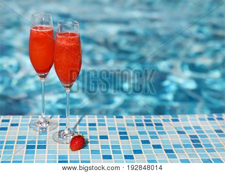 Champagne glasses with strawberry on turquoise background. Rossini cocktail. Summer pool party