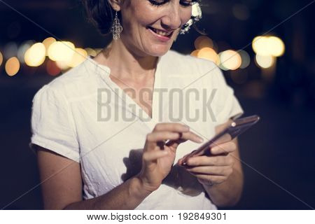 Woman using smart phone walking on street night time