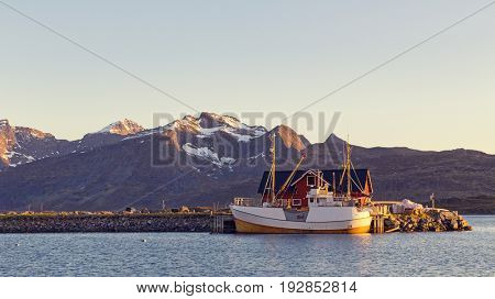 Fishing boats in harbor at midnight sun in Northern Norway, Lofoten Island, Ramberg, Norway - Mountain In Background