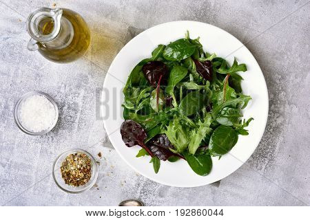 Healthy green salad with leaves of spinach arugul on light background. Top view