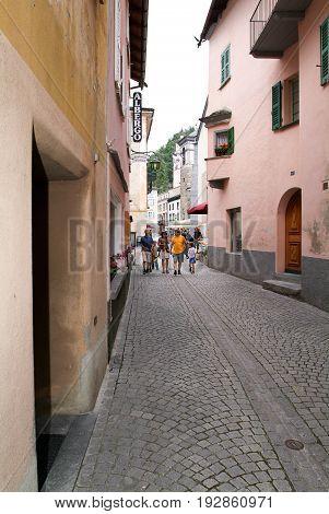 Poschiavo, Switzerland - 20 July 2015: People walking on a narrow street of Poschiavo on the Swiss alps