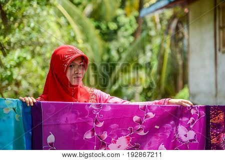 KRABI THAILAND - MAY 2 2015: Muslim woman drying Batik fabric outside home in Lanta island of Krabi Thailand