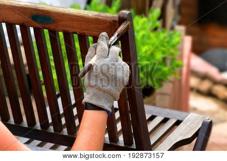 Painting and applying protective varnish on a wooden garden chair