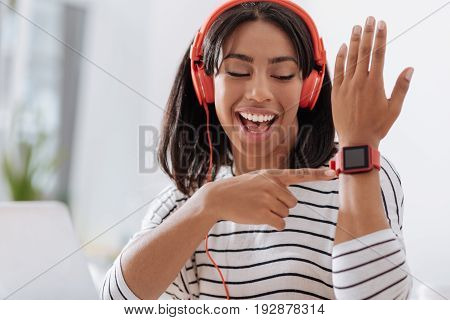Smart watch. Happy joyful young woman smiling and looking at you while pointing at her smart watch