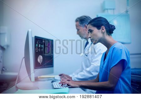 Human brain with various medical reports against concentrated male doctor with nurse working on computer