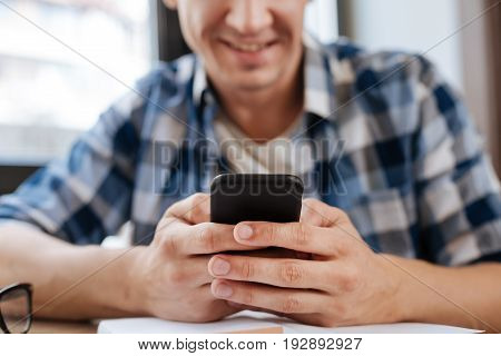 Instant access. Energetic adventurous savvy man using his smartphone for communicating online and sharing news through social networks