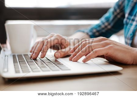 Digital age. Productive quick witted persistent woman sitting in a public place and feeling inspired while typing an essay on her computer