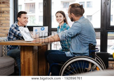 Positive prognosis. Quick witted intelligent helpful man showing his friends some data while discussing prospects of their startup in a cafe