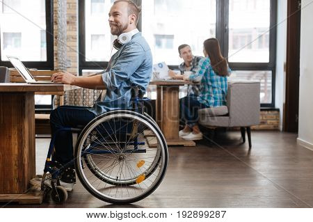 Productive atmosphere. Attentive thoughtful persistent guy sitting at the table and enjoying working atmosphere while writing his academic work