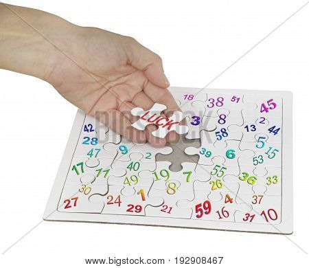 Luck and lottery numbers jigsaw puzzle - female hand holding a jigsaw piece with the word LUCK on it with a lottery numbers jigsaw beneath  isolated on white background