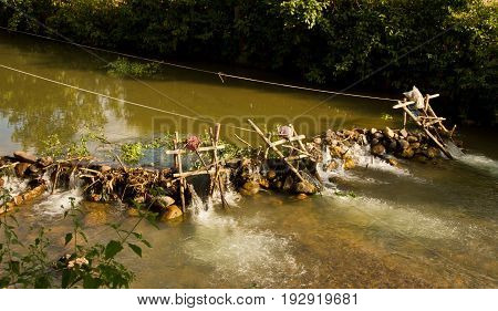 Improvised run-of-stream micro hydro electricity generation. Using boat propellers in rapids driving shafts to electric motors, all supported on bamboo scaffolding. Nam Ou River, Laos