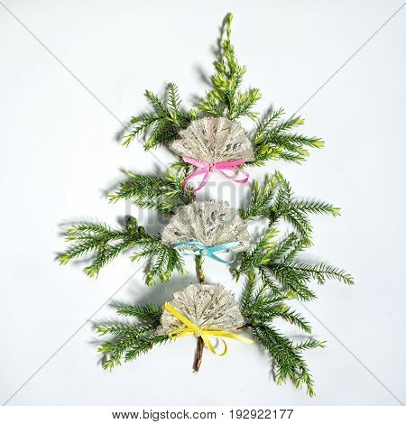 flat lay small christmas tree made from fir branches decorated with three fans, isolated on white background. new year and christmas concept of spanish, mexican or chinese fans.