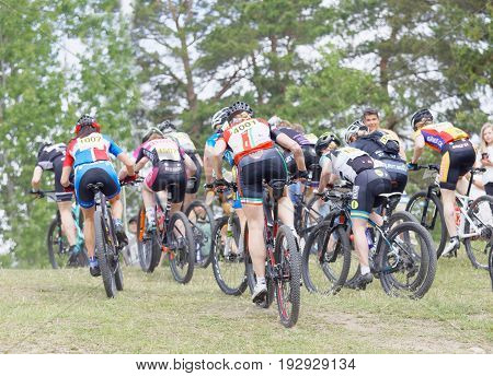 STOCKHOLM SWEDEN - JUNE 11 2017: Rear view of female mountain bike cyclists struggling in a steep uphill at Lida Loop Mountain bike Race. June 11 2017 in Stockholm Sweden