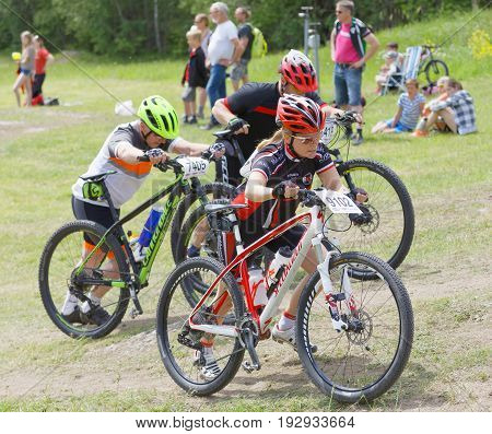 STOCKHOLM SWEDEN - JUNE 11 2017: Woman leading her mountain bike uphill at Lida Loop Mountain bike Race audience in background. June 11 2017 in Stockholm Sweden
