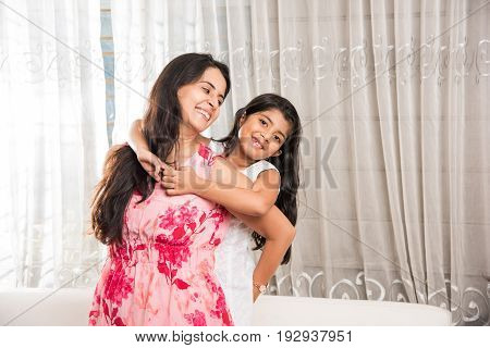 indian smart mother hugging her cute daughter, Portrait of happy Indian mother and daughter together while sitting on sofa