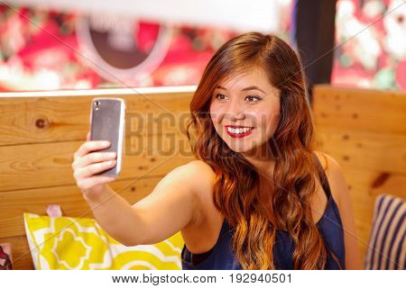 Smiling beautiful woman spending time in a bar, is taking a selfie herself.