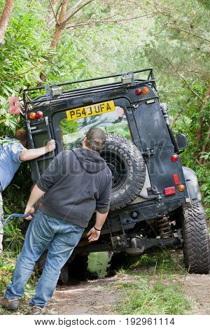BEAULIEU HAMPSHIRE UNITED KINGDOM - JUNE 25 2017 Land Rover day with many varieties of Land Rovers this Land Rover has slipped off a dusty off road track in the woods and got stuck roof rack caught in trees.