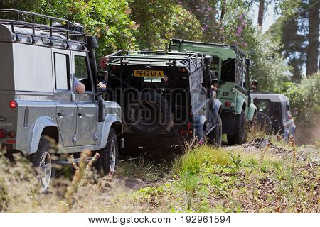 BEAULIEU HAMPSHIRE UNITED KINGDOM - JUNE 25 2017 Land Rover day with many varieties of Land Rovers these are driving in a row on a dusty off road track in the woods.