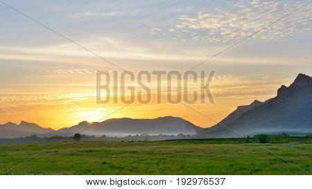 Sunset background photo of outdoor countryside meadow spring nature under sky and cloudsRural pasture landscape of plain grass background