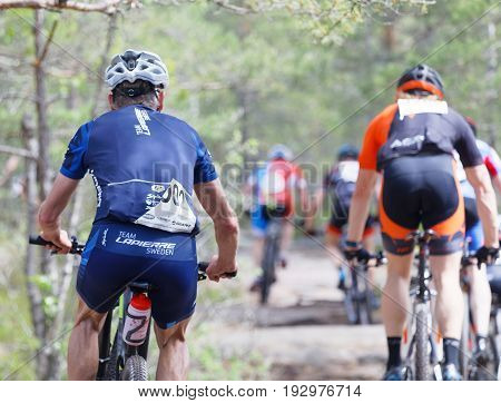 STOCKHOLM SWEDEN - JUNE 11 2017: Rear view of group of mountain bike cyclists in the forest at Lida Loop Mountain bike Race. June 11 2017 in Stockholm Sweden