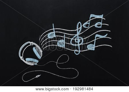 headphones with wire and musical notes drawn on black chalkboard