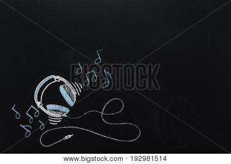 Headphones With Wire And Musical Notes Drawn On Black Chalkboard