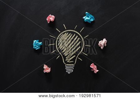 top view of paper rubbish lying around of electric bulb drawn on blackboard
