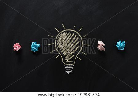 top view of paper rubbish with electric bulb drawn on blackboard