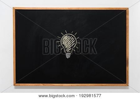 electric bulb drawn on black chalkboard in wooden frame
