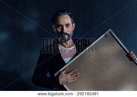 A Handsome Man With A Beard On A Black Wall Background. In The Hands Of A Man Picture. A Beard And A
