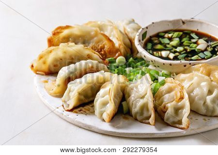 Fried Asian Dumplings Gyozas Potstickers In White Ceramic Plate Served With Bowl Of Soy Onion Sauce 