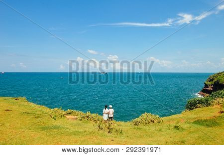 Chinese Couple Together On Field Of Grass, Looks At Ocean, On Weizhou Island At Beihai City, Guangxi