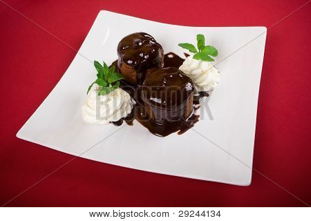 Close-up chocolate cake with cream and mint leafs on red background