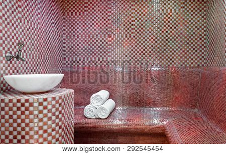 Traditional Turkish Hamam With Stone Walls, Sink And Stack Of  Towels