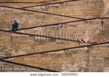 Man And Woman Laying On The City Walls, Old City Of The Three Cities, Malta