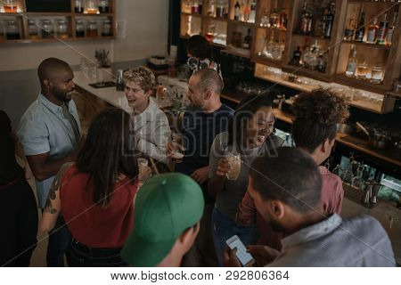 Diverse Young Friends Talking Over Drinks In A Bar