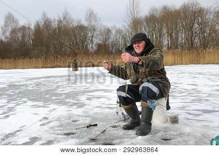 Man Ice Fishing On A Frozen Lake. Winter Holidays And People Concept. Winter Fishing, Ice Fishing. B