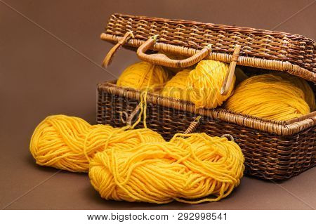 Balls Of Wool For Knitting Yellow In A Wicker Wooden Basket On The Brown Background