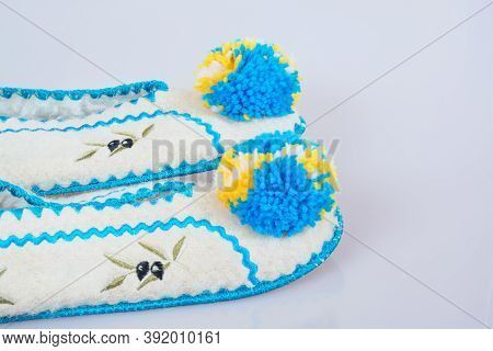 Pair Of Woolen Slippers With Blue Pumpons On Gray Background