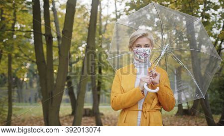 Beautiful Caucasian Woman With Face Mask Holding With Transparent Umbrela In The Park In Autumn. Hig