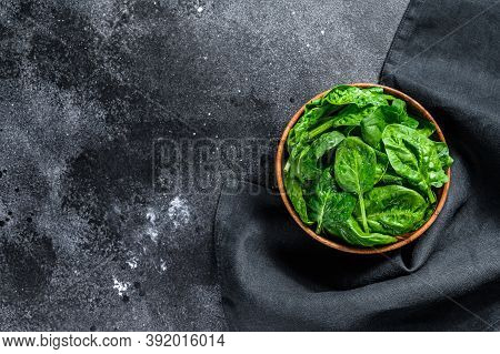Young Raw Spinach In A Wooden Bowl. Black Background. Top View. Copy Space