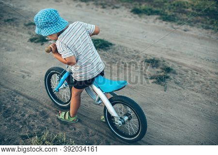 Upper View Photo Of A Caucasian Boy With Hat Riding The Bike On A Country Road In A Summer Day