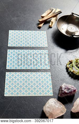 cartomancy, occult science and divination concept - tarot cards and different staff for magic ritual on slate stone background