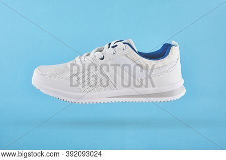 White Sports Sneakers Levitate On A Blue Background. Stylish Man Sneakers For Fitness. White Sneaker