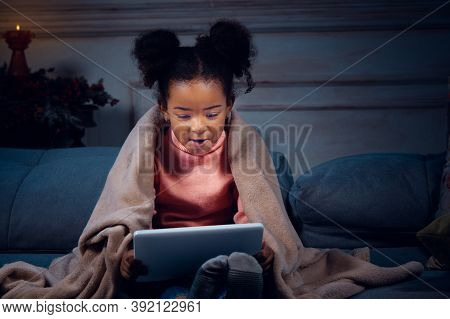 Happy African-american Little Girl During Video Call With Laptop And Home Devices, Looks Delighted A